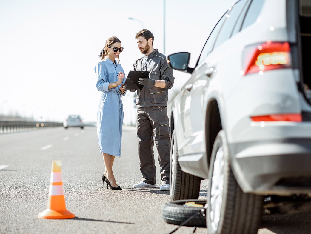 Une femme avec une voiture en panne recevant de l'assistance routière.